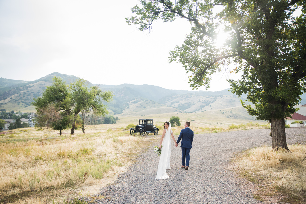 A bride and groom walking down a dirt road in the mountains in Colorado.