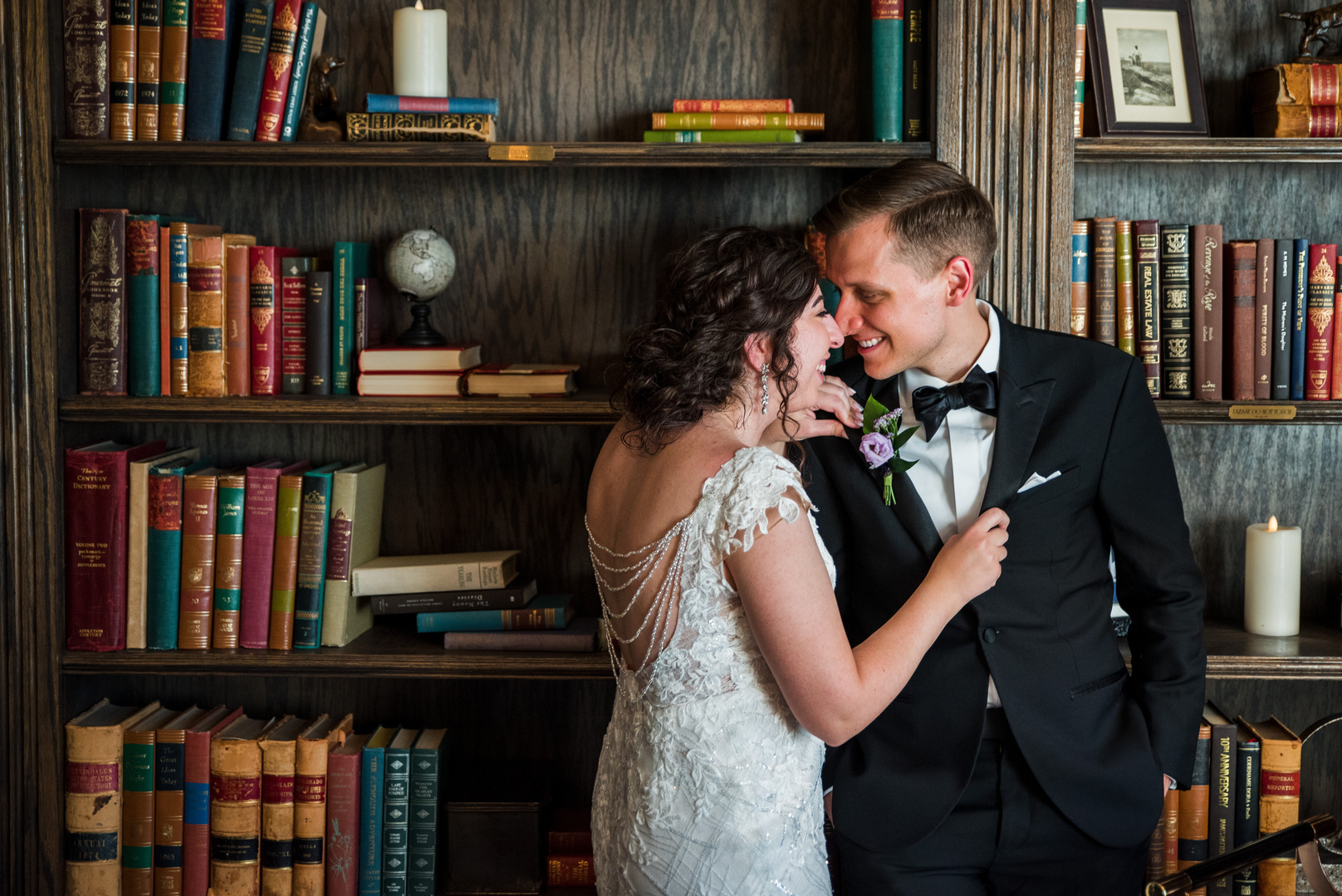 A bride and groom in front of bookshelf in The Manor House library.