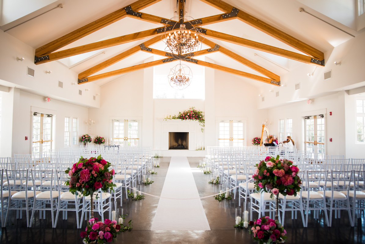 A wedding ceremony set up in a large room at The Manor House with white chairs.