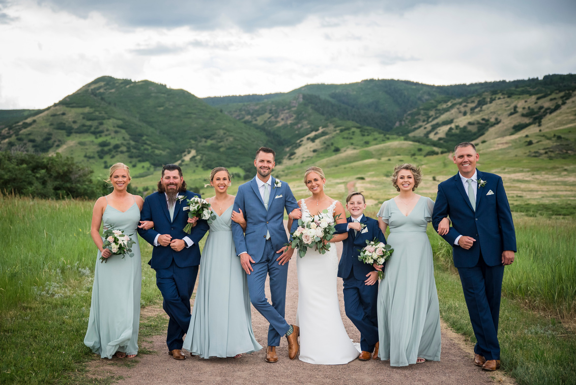 A group of bridesmaids and groomsmen pose for a photo in front of the mountains at The Manor House.