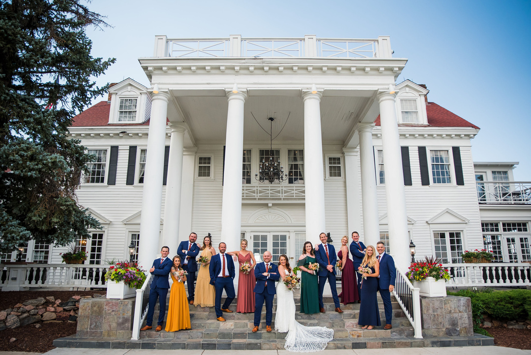 A wedding party poses for a photo in front of the mansion at The Manor House in Littleton, Colorado.