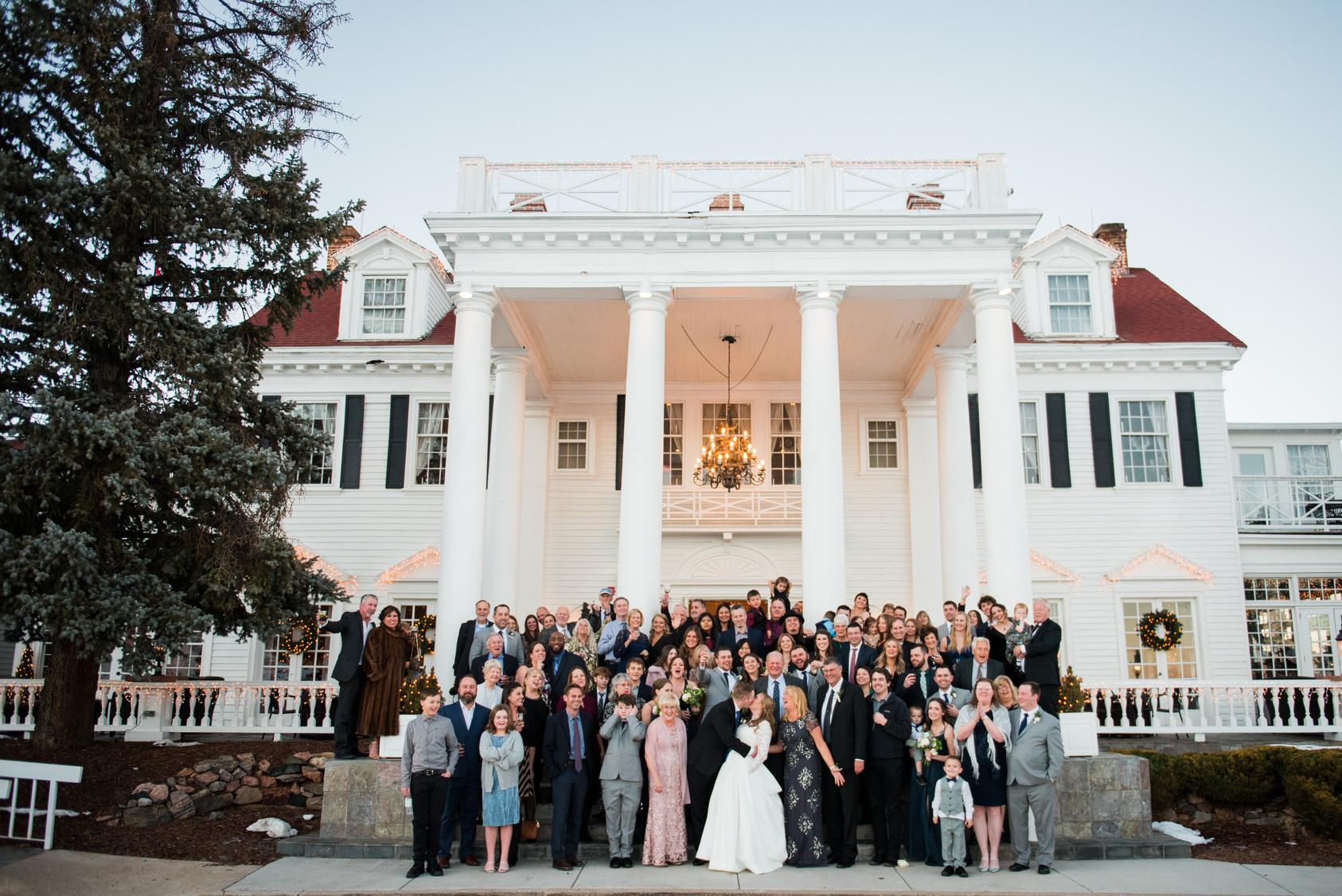 Wedding guests pose for a photo in front of the mansion at The Manor House, captured by Denver, Colorado wedding photographer Two One Photography.