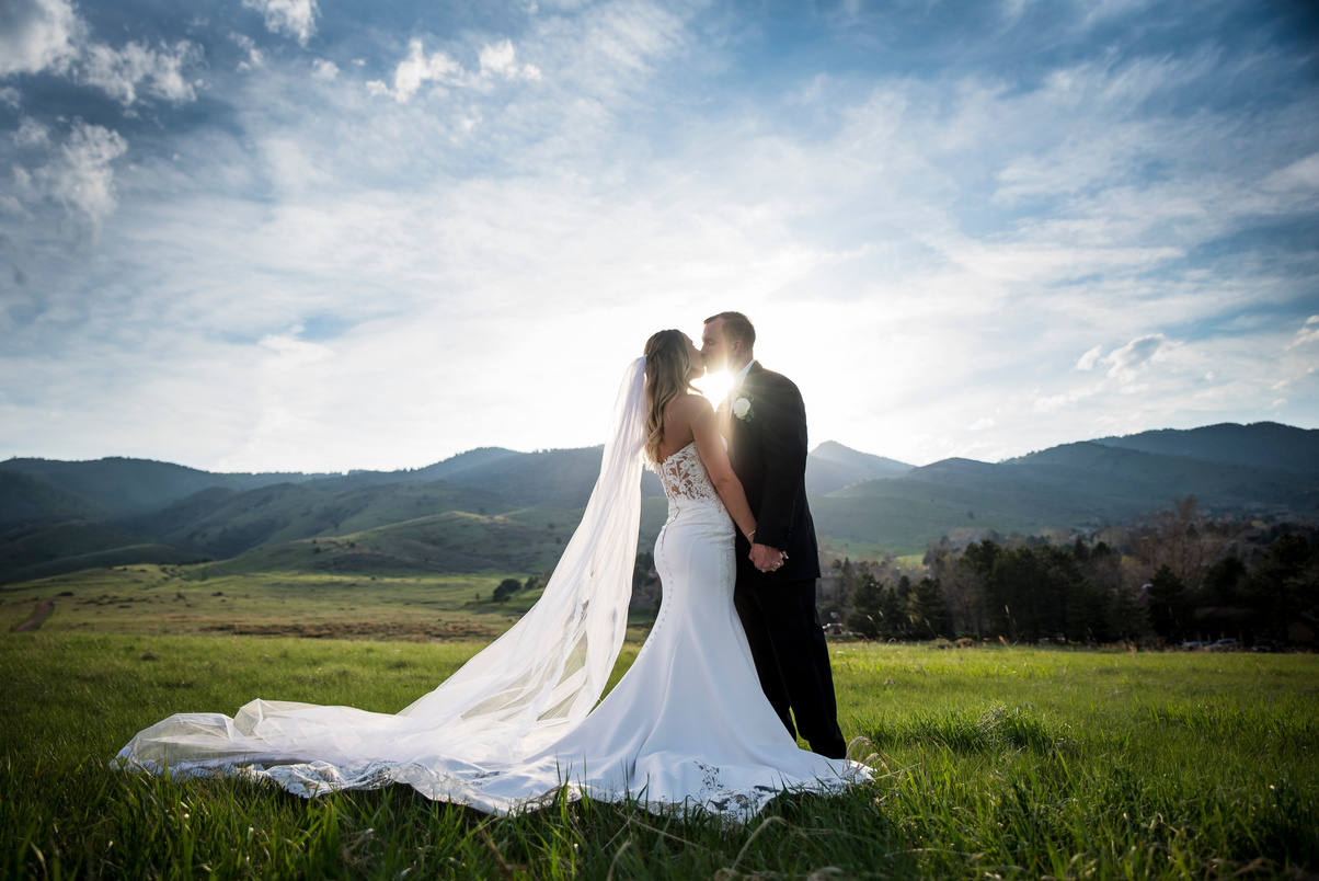 A bride and groom in a field with mountains in the background at The Manor House in Littleton, Colorado.