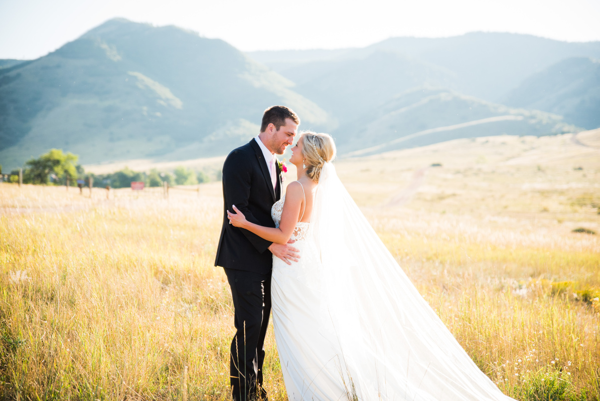A bride and groom embrace in a golden field at The Manor House in Littleton, Colorado.